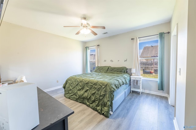 bedroom featuring visible vents, multiple windows, baseboards, and wood finished floors