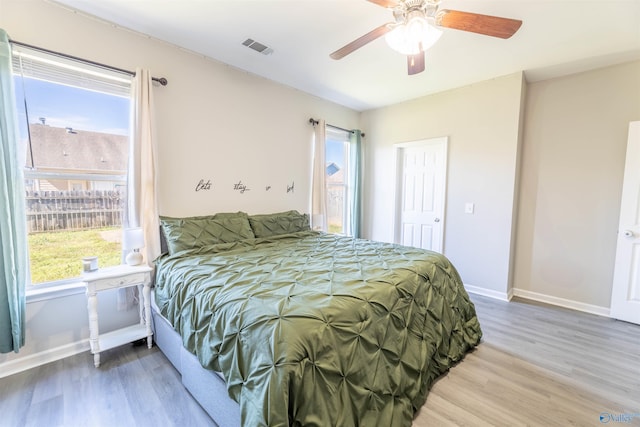 bedroom with visible vents, a ceiling fan, baseboards, and wood finished floors