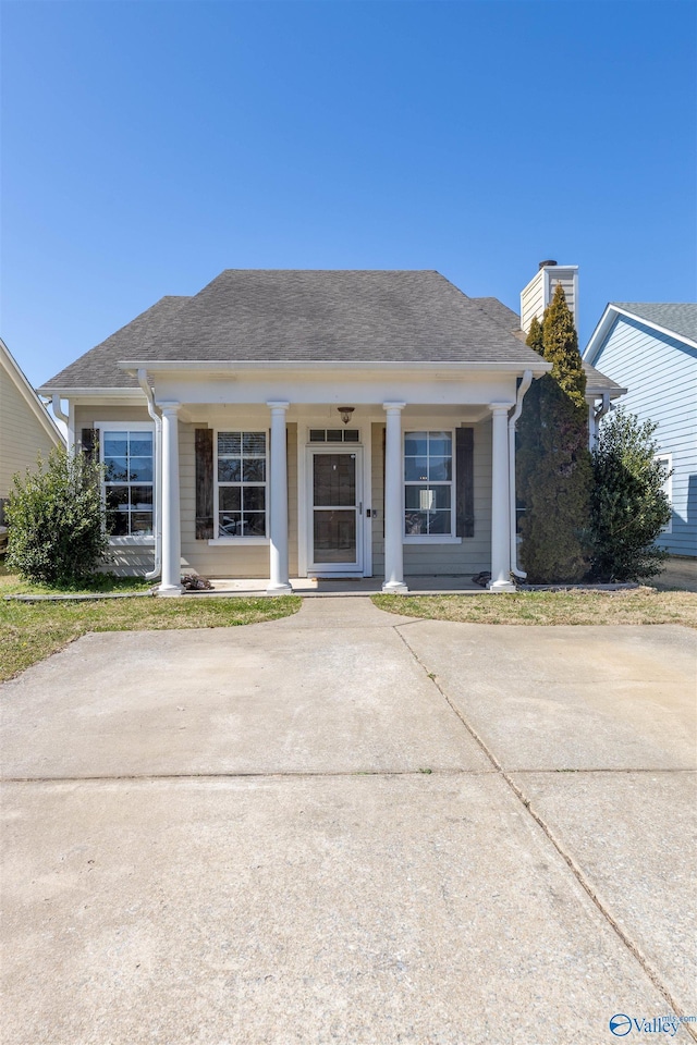 bungalow featuring a shingled roof, covered porch, and a chimney