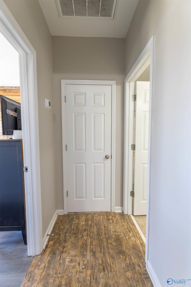 corridor featuring dark wood finished floors, visible vents, and baseboards