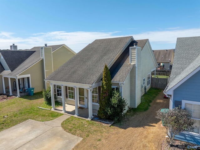 view of side of property with fence, a lawn, roof with shingles, and a patio area