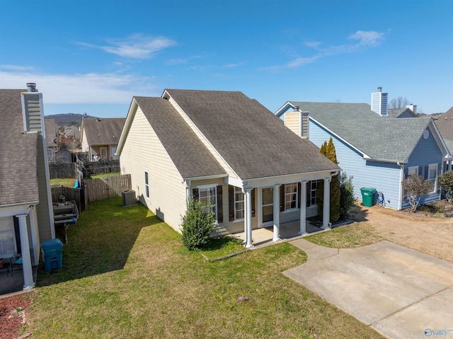 view of front of property with fence, central AC, a front yard, roof with shingles, and a patio area