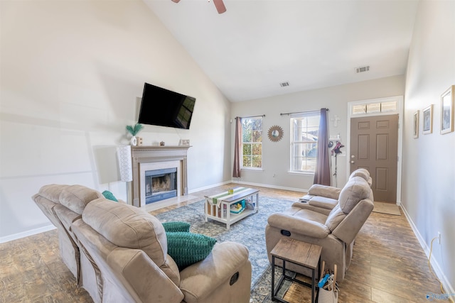 living room featuring a fireplace with flush hearth, wood finished floors, visible vents, and baseboards