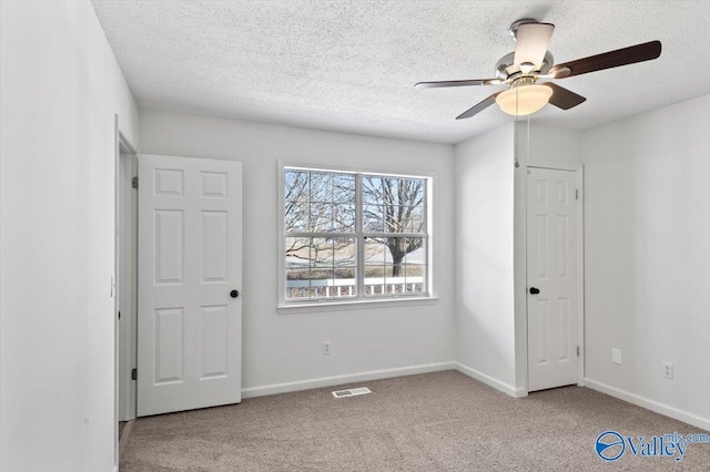 unfurnished bedroom featuring ceiling fan, light carpet, and a textured ceiling