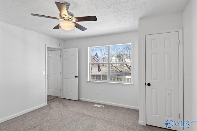 unfurnished bedroom featuring ceiling fan, light colored carpet, and a textured ceiling