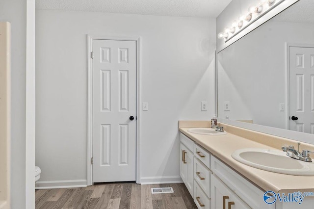 bathroom with vanity, hardwood / wood-style flooring, toilet, and a textured ceiling