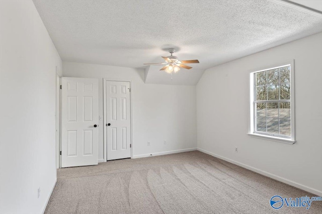 unfurnished bedroom with vaulted ceiling, light colored carpet, ceiling fan, a textured ceiling, and a closet