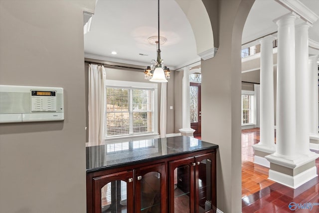 interior space with crown molding, decorative columns, and dark hardwood / wood-style floors