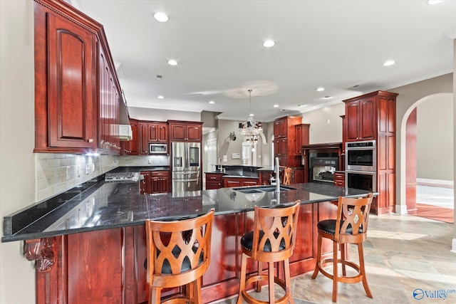 kitchen with tasteful backsplash, ornamental molding, a kitchen breakfast bar, stainless steel appliances, and a kitchen island with sink