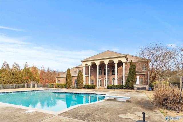 view of swimming pool featuring a diving board and a patio area