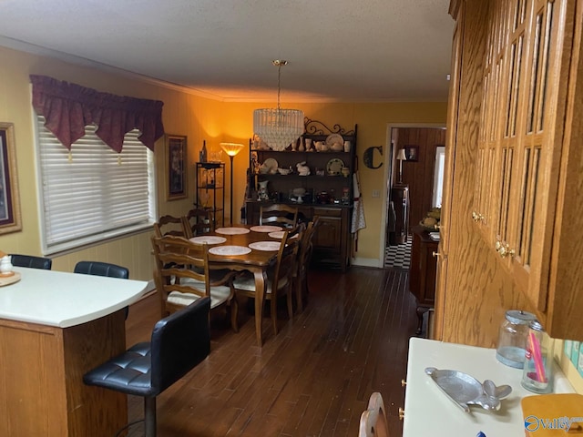 dining area featuring an inviting chandelier, crown molding, and dark wood finished floors