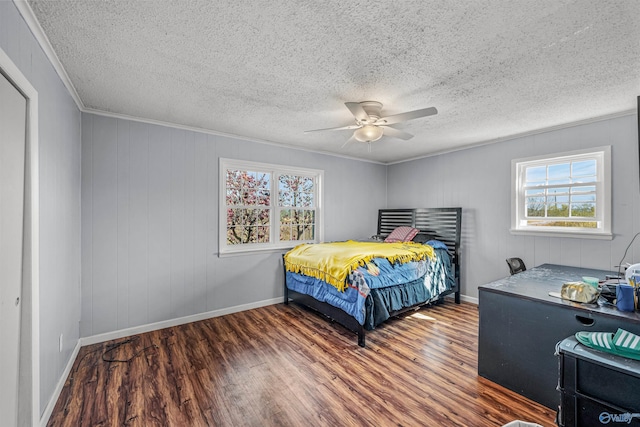 bedroom featuring ceiling fan, baseboards, wood finished floors, and crown molding