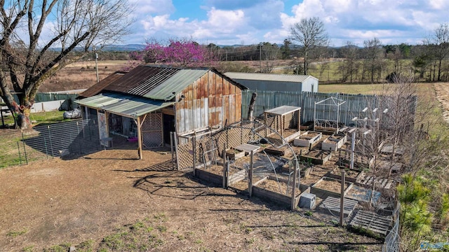 view of outbuilding featuring an outdoor structure, a vegetable garden, and fence