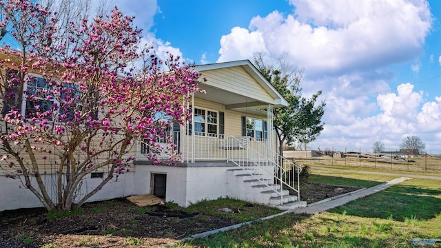 view of front of property featuring stairs, covered porch, a front yard, and fence