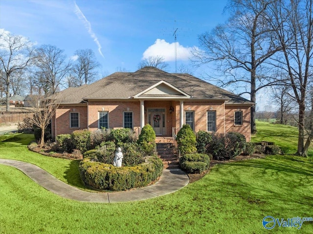view of front of house with brick siding, roof with shingles, and a front yard