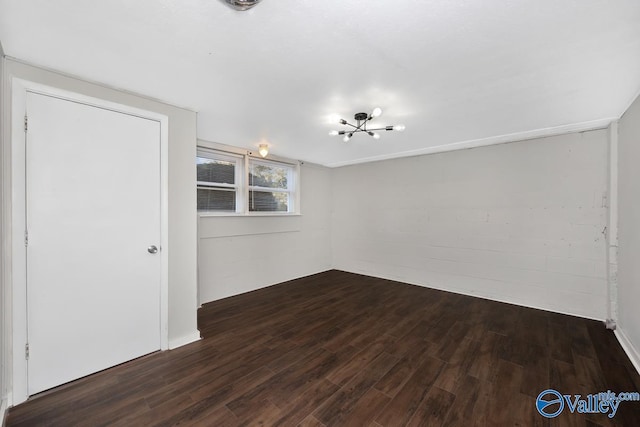 unfurnished room with dark wood-type flooring and a chandelier