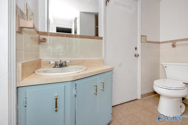 bathroom featuring tile patterned flooring, vanity, tile walls, and toilet