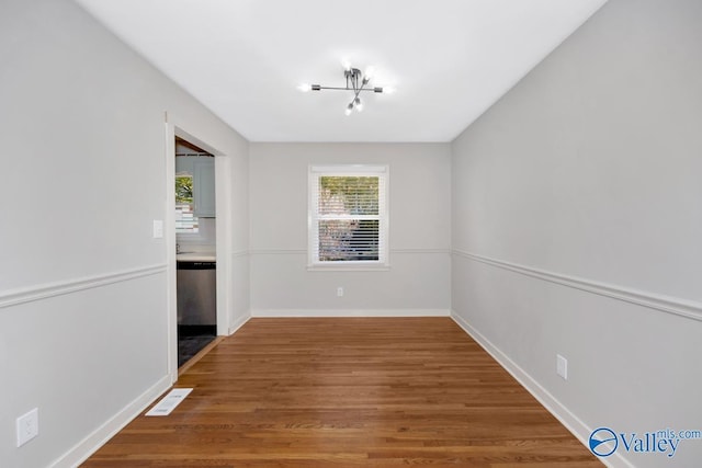 spare room with wood-type flooring and a chandelier