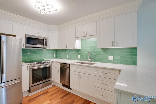 kitchen with white cabinetry, tasteful backsplash, light wood-type flooring, stainless steel appliances, and sink