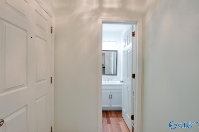 corridor with sink and light hardwood / wood-style flooring