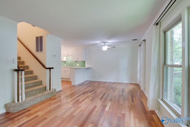 unfurnished living room with ceiling fan, ornamental molding, sink, and light hardwood / wood-style flooring