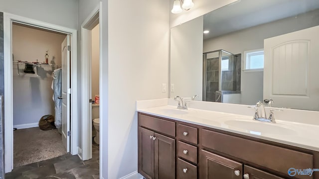 7607 NW Ashor Dr, Huntsville, AL 35806 - bathroom featuring double vanity, a walk in closet, and a shower with shower door