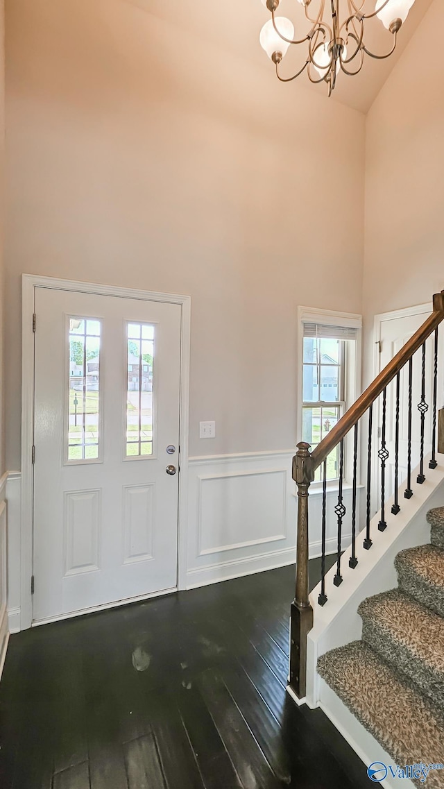 7607 NW Ashor Dr, Huntsville, AL 35806 - foyer entrance featuring dark wood-type flooring, healthy amount of natural light, wainscoting, a towering ceiling, and a chandelier