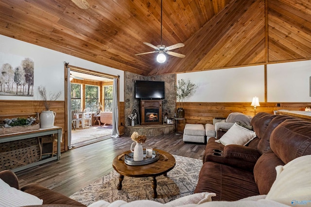 living room featuring vaulted ceiling, wood walls, a fireplace, dark hardwood / wood-style flooring, and ceiling fan