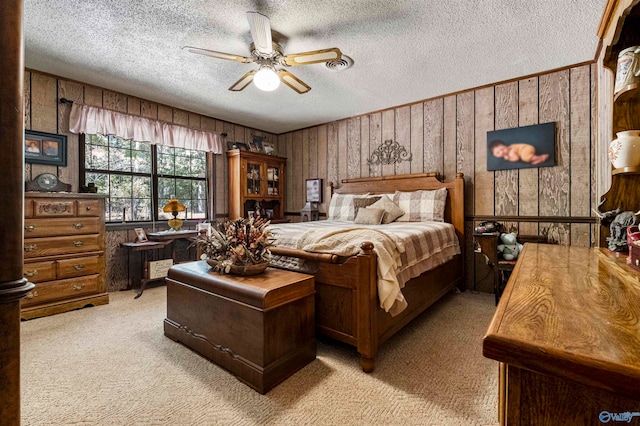 carpeted bedroom with wooden walls, a textured ceiling, and ceiling fan