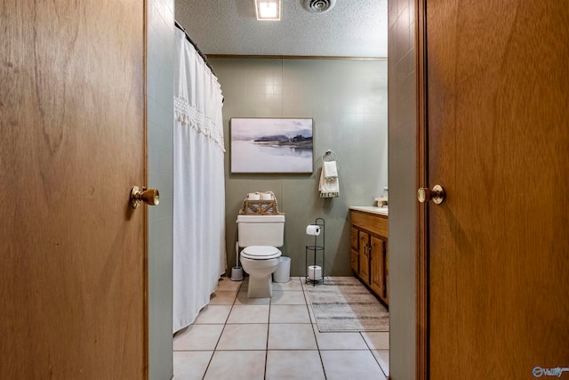 bathroom with tile walls, tile patterned flooring, a textured ceiling, vanity, and toilet