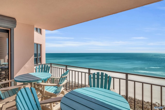 balcony with visible vents, a water view, and a beach view