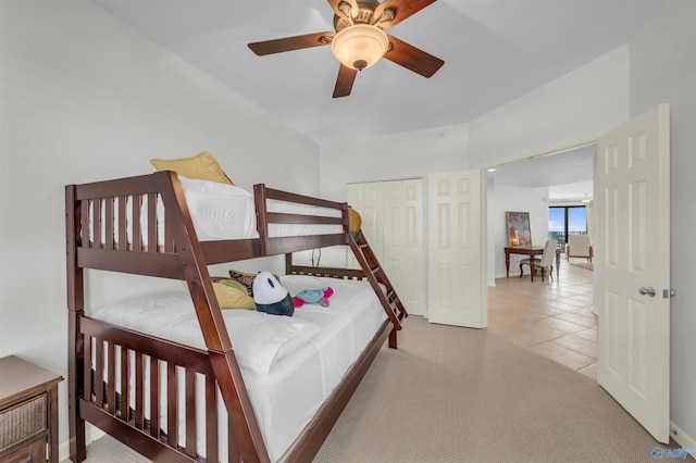 carpeted bedroom with a closet, a ceiling fan, and tile patterned floors