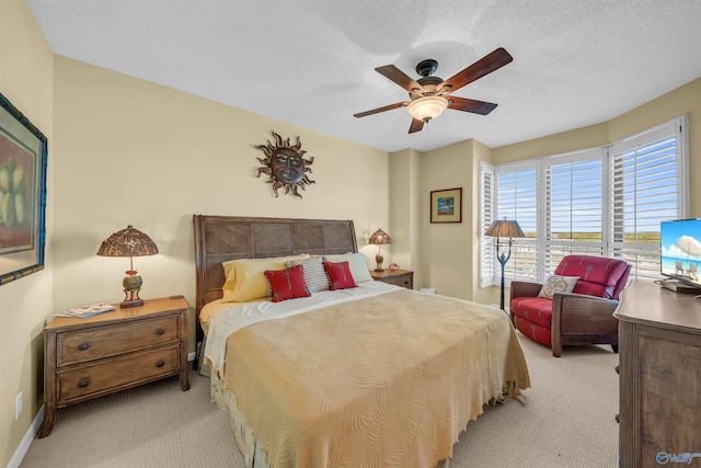 bedroom with a ceiling fan, light colored carpet, a textured ceiling, and baseboards