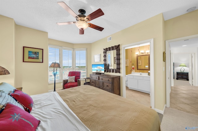 bedroom featuring light tile patterned floors, visible vents, a textured ceiling, and ensuite bathroom