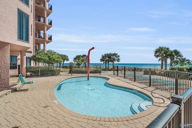 pool featuring a water view, fence, and a patio