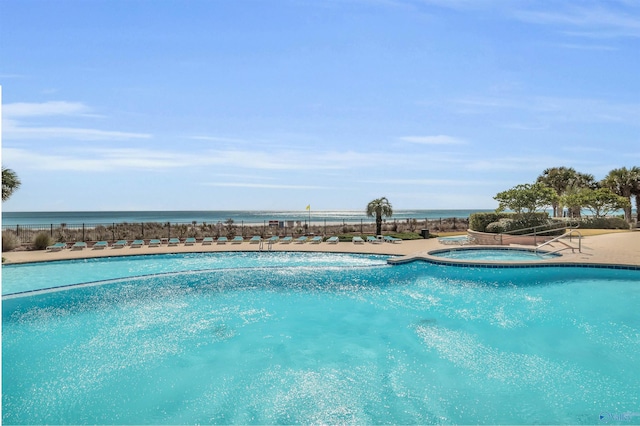 pool featuring a water view, a hot tub, fence, and a patio