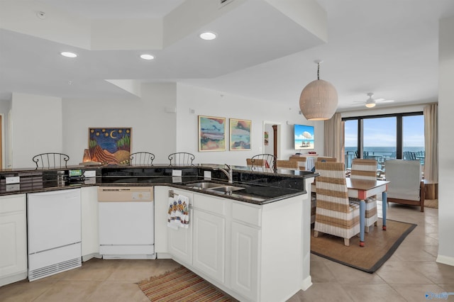 kitchen featuring recessed lighting, light tile patterned flooring, a sink, dark stone countertops, and dishwasher