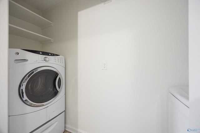 clothes washing area featuring washer and dryer, laundry area, and baseboards