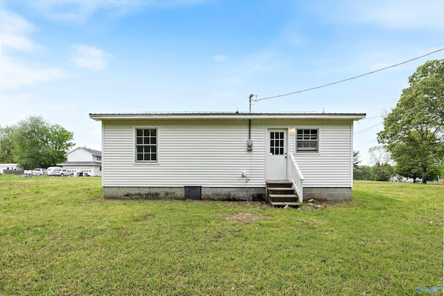 rear view of house with entry steps, metal roof, and a yard