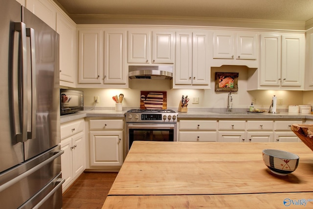 1625 River Bend Pl SE, Decatur, AL 35601 - kitchen with stainless steel appliances, under cabinet range hood, white cabinetry, and ornamental molding
