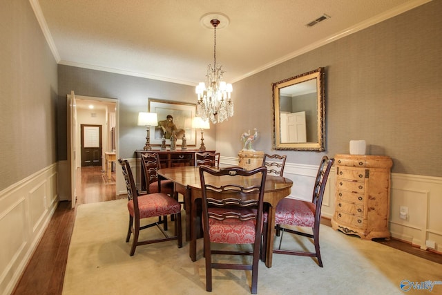 1625 River Bend Pl SE, Decatur, AL 35601 - dining area featuring crown molding, a chandelier, a decorative wall, a wainscoted wall, and wood finished floors