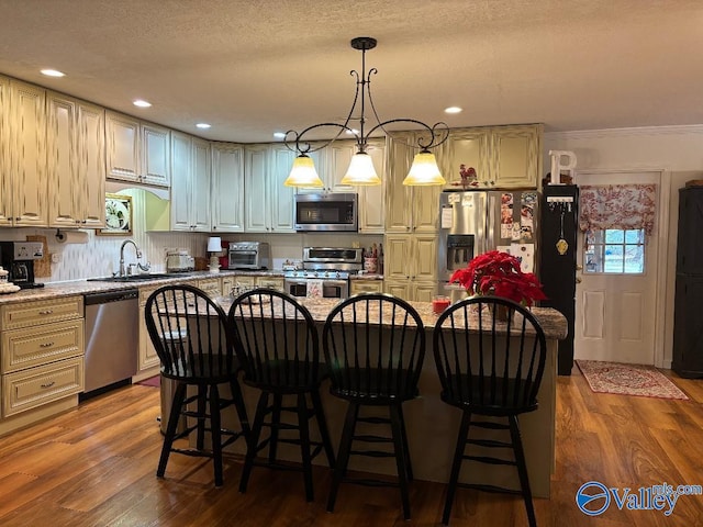 kitchen with a center island, stainless steel appliances, light stone countertops, and sink