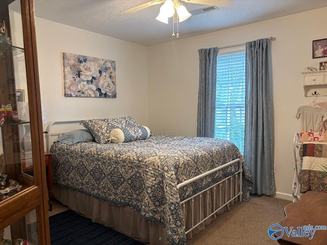 bedroom with ceiling fan, carpet floors, and a textured ceiling