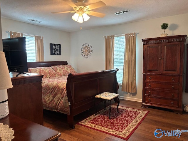 bedroom featuring ceiling fan, dark hardwood / wood-style flooring, and a textured ceiling