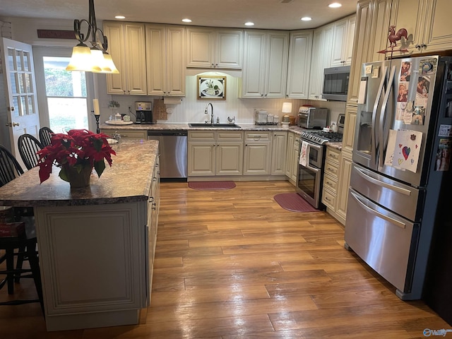 kitchen featuring a kitchen bar, decorative light fixtures, a center island, dark stone countertops, and stainless steel appliances