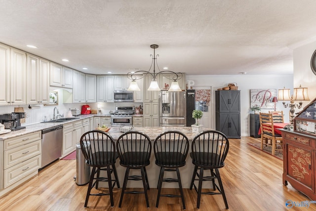 kitchen featuring light stone counters, hanging light fixtures, a kitchen island, and appliances with stainless steel finishes