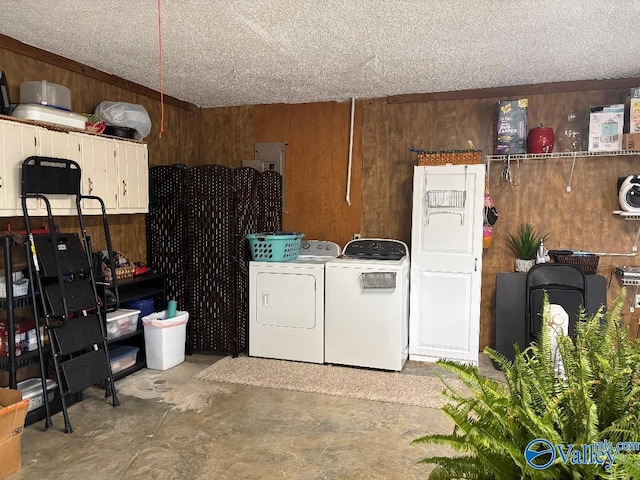 clothes washing area featuring a textured ceiling, washing machine and clothes dryer, and wooden walls