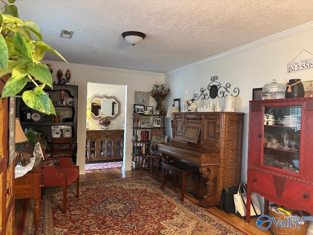 miscellaneous room with hardwood / wood-style flooring, ornamental molding, and a textured ceiling