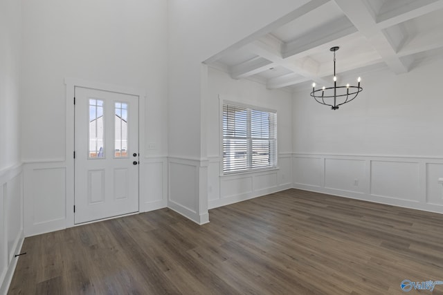 entrance foyer with beam ceiling, coffered ceiling, wainscoting, a chandelier, and dark wood-style flooring