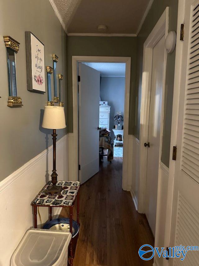 hallway featuring a textured ceiling, dark wood-style flooring, and crown molding